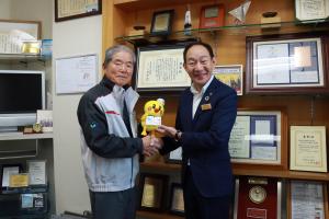 記念品のひなちゃんぬいぐるみを受け取る梶野相談役