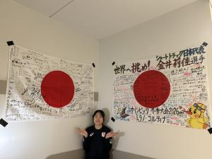 部屋に飾った寄せ書きとポーズをとる金井選手